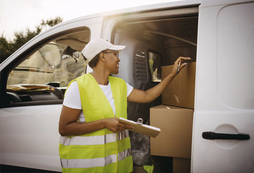 delivery driver counting cardboard boxes in van